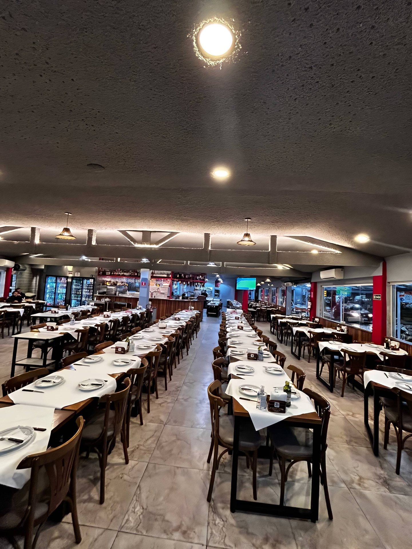 Salão do Smarc Grill com mesas postas e bar ao fundo